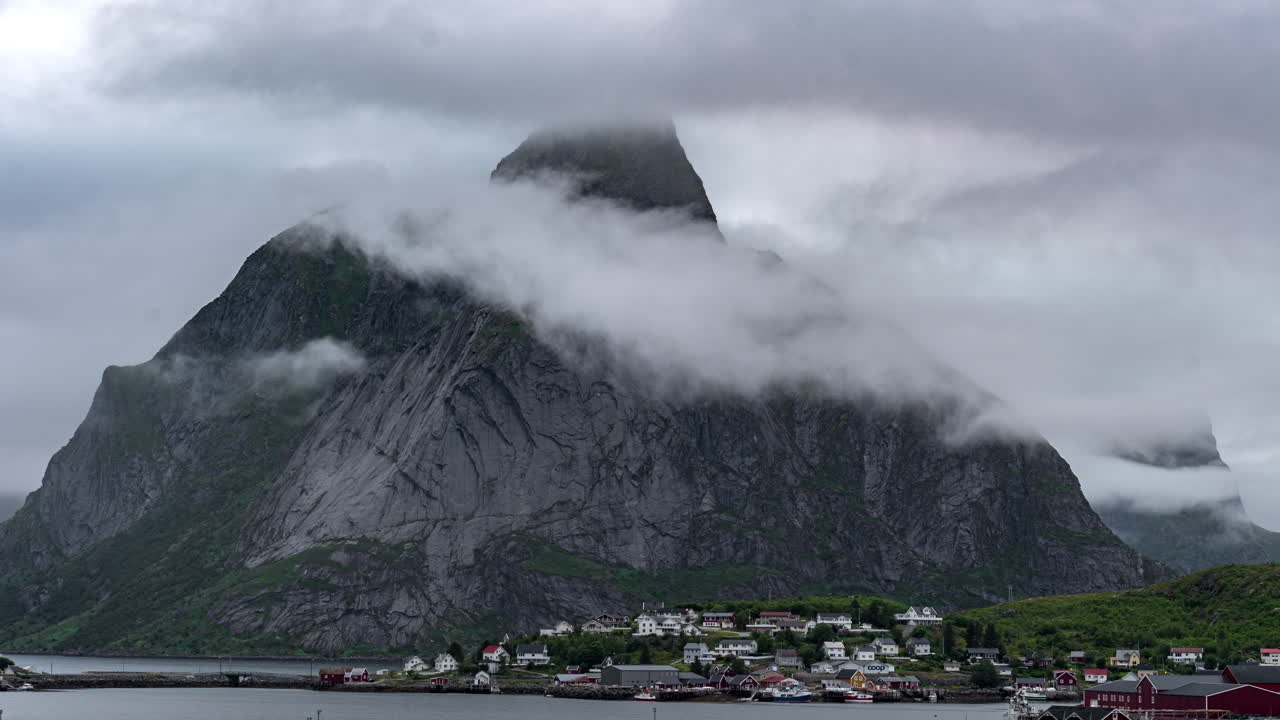 Villaggio di pescatori di Reine e cima di montagna rocciosa circondata dalle nuvole, Norvegia
