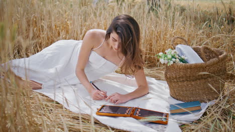 dreamy girl sketching album relaxing blanket at rye landscape. model drawing