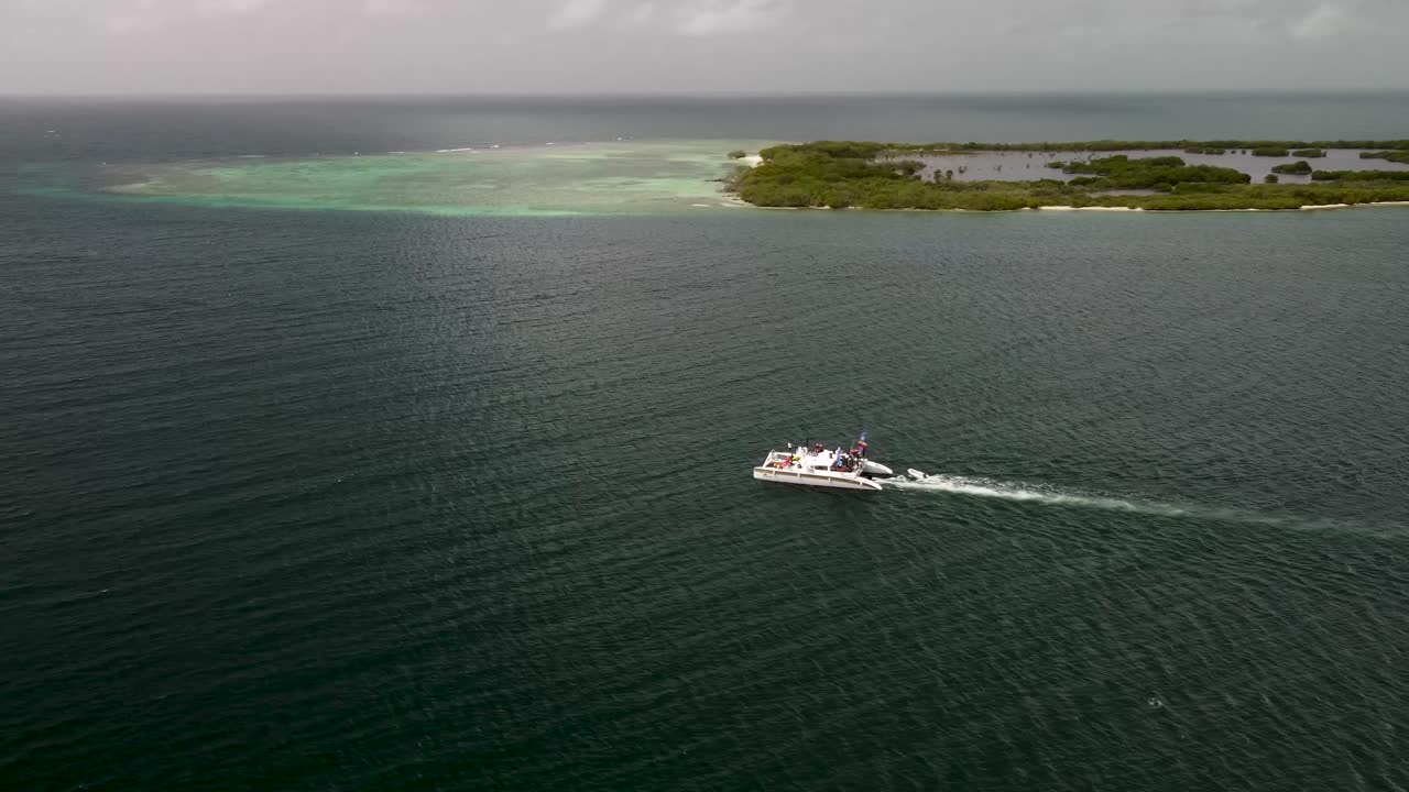 Aerial shot of a catamaran or boat sailing through a sea with islets, in Tucacas, Venezuela.