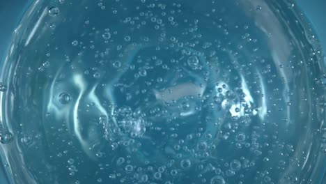 top view of a spinning surface of clear blue water with air bubbles top view of a spinning surface of clear blue water with air bubbles transparent liquid with circular rotation aqua whirlpool twisting and bubbling blue fluid mixer with water turning in a circle macro shot of water texture