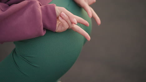 close up of lady slightly bent in green leggings, with hand pointing out during fitness exercise, focusing on body posture and movement in outdoor training session