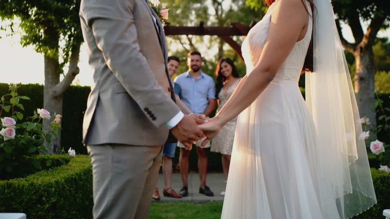 La telecamera zooma su sposi che si scambiano le promesse e si tengono per mano in giardino, con l'abito da sposa e la boutonnière.
