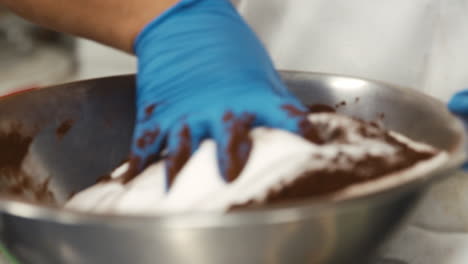panadería mezclando masa de galletas en un cuenco con su mano, cerca