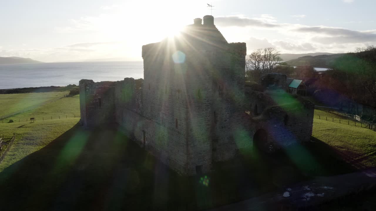 FLYGFOTO - Skipness Castle en solig dag, Kintyre, Skottland, bred åkning åt höger.