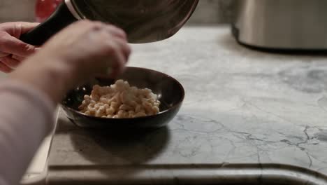 woman serving pasta into bowl in slow motion