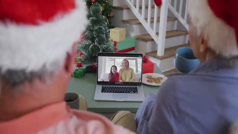 Senior-caucasian-couple-on-video-call-with-adult-daughter-and-granddaughter-at-christmas-time