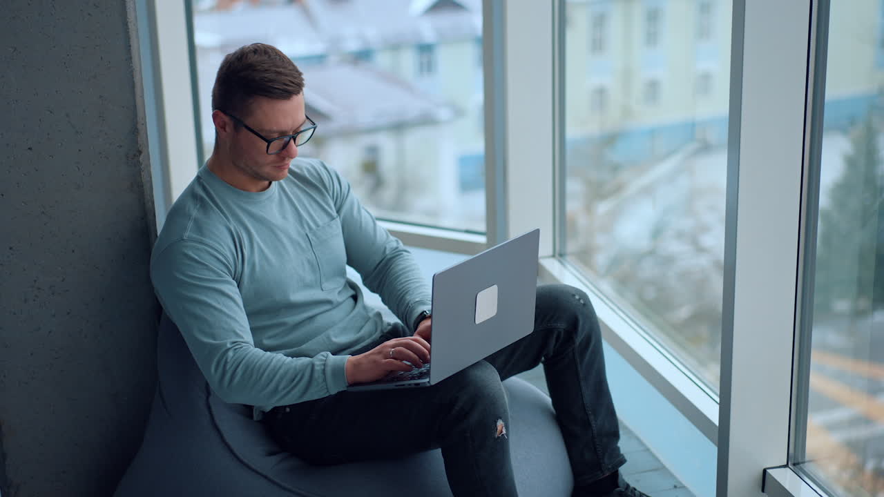 hombre trabajando en una computadora portátil por la ventana