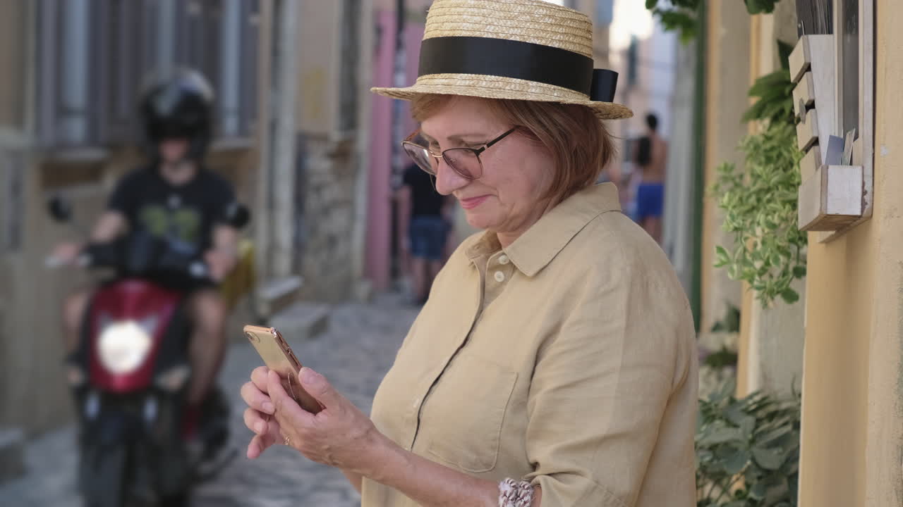 유럽 도시 거리에서 스마트폰을 사용하는 고령 여성