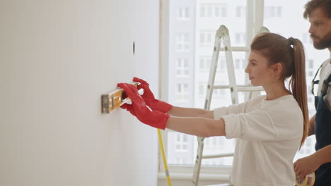 couple measuring and leveling a wall for installation