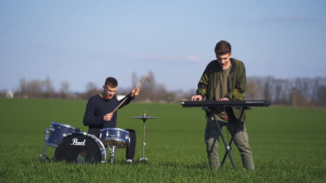 guys playing musical instruments in the beautiful green plantations. drummer and piano musician performing in the blurred nature backdrop.