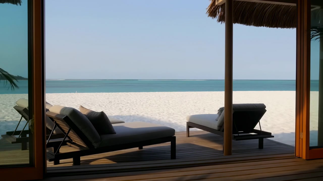 Kirkas lomakeskuksen terassi, josta on näkymä trooppiselle rannalle, aurinkotuoleineen puukannella, tyynine turkooseine vesineen ja selkeine horisontteineen pehmeässä päivänvalossa.