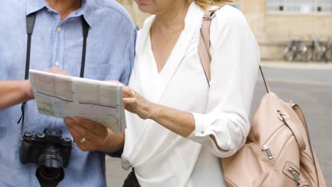 Mid-Section-of-Tourist-Couple-on-City-Break-Reading-Map