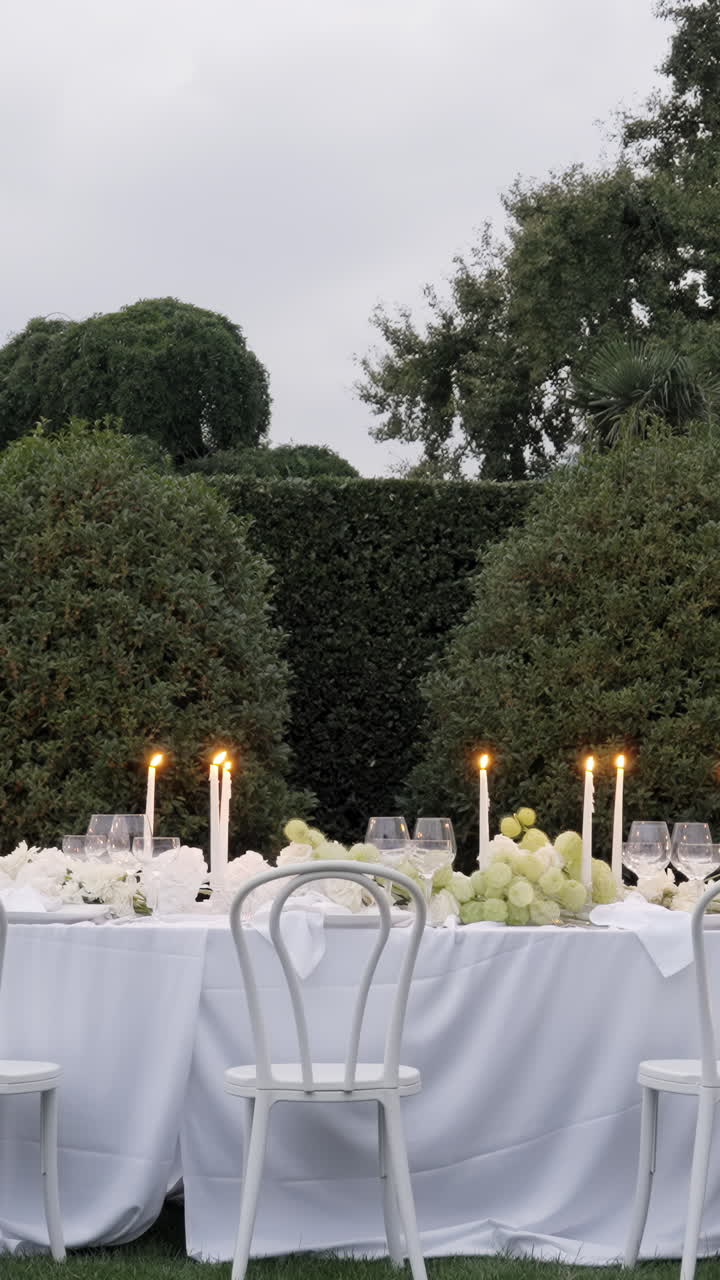 Elegante apparecchiatura per cena all'aperto con candele accese e decorazioni floreali al tramonto