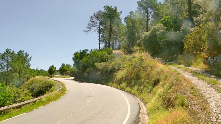 Strada curva vuota attraverso la montagna in una giornata di sole estiva
