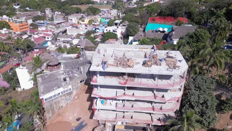 Un-Dron-Captura-A-Los-Trabajadores-De-La-Construcción-En-La-Cima-De-Un-Nuevo-Edificio-Que-Se-Está-Construyendo-Sobre-Una-Montaña-En-Sayulita,-México.