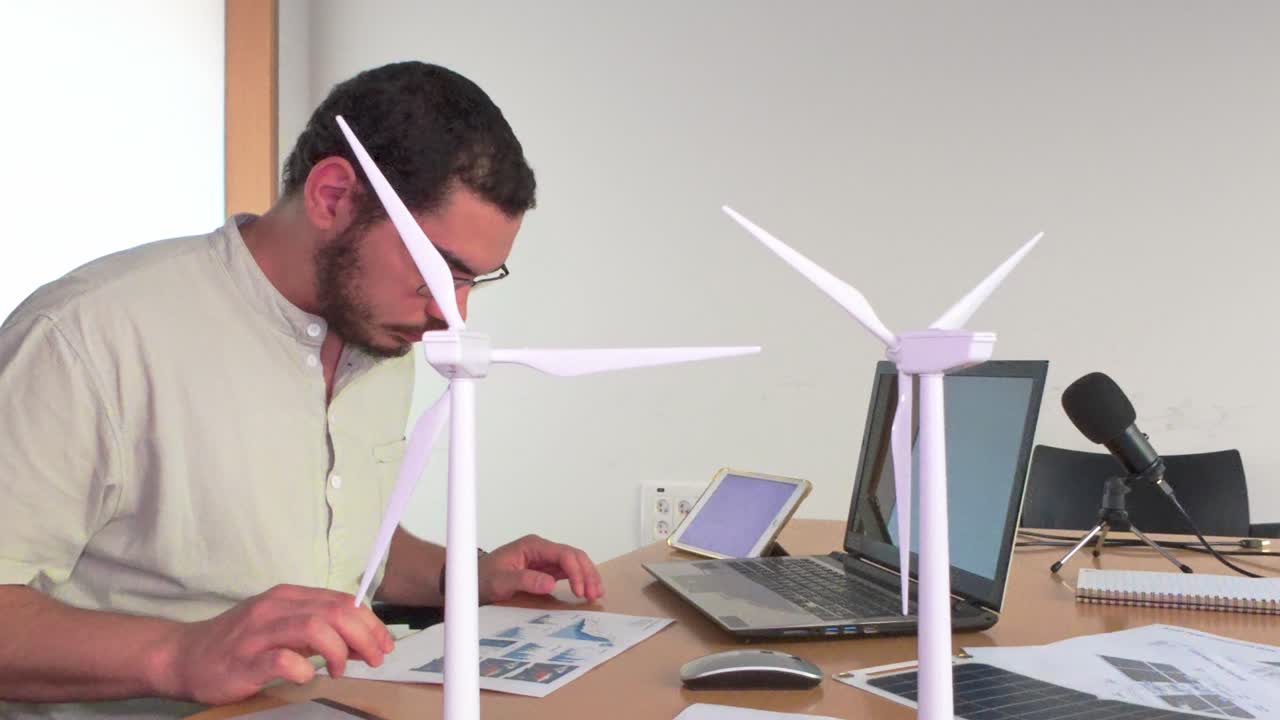 A man working on a renewable energy project with wind turbine models