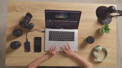 person working on a laptop with camera and photo editing software