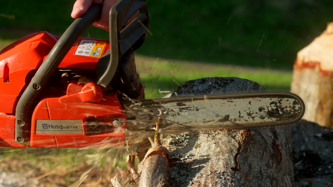 Man Using Lightweight Battery-Powered Chainsaw Cutting Log. Close-up Shot