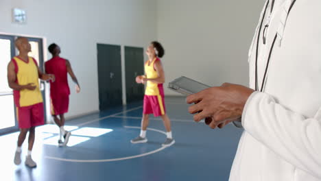 Trainer-Hält-Ein-Tablet-Auf-Einem-Basketballplatz,-Mit-Kopierplatz