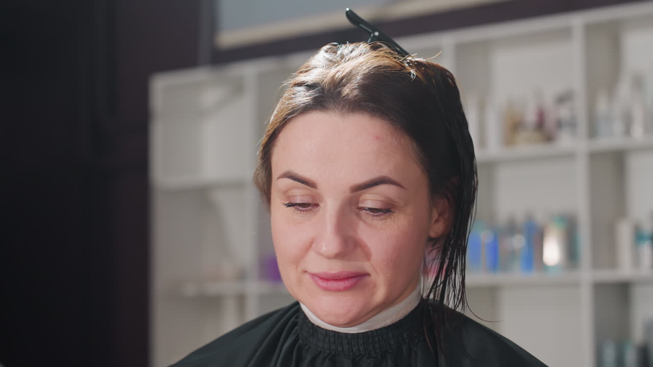 procedura di colorazione dei capelli, stilista autorizzato che applica la tinta mentre il cliente rimane comodamente protetto, processo di colorazione dei capelli eseguito da esperti con il cliente accuratamente coperto e in paziente attesa