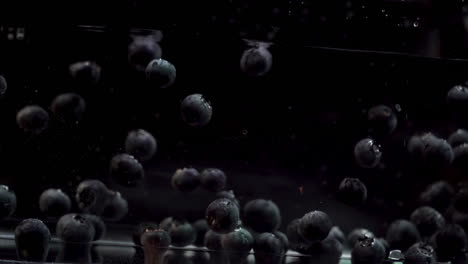 Blueberries-Floating-In-Water-Against-Black-Background-in-Slow-Motion