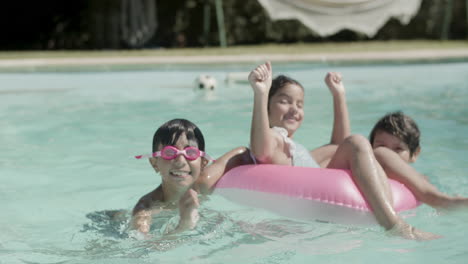 happy children playing with rubber ring in swimming pool.