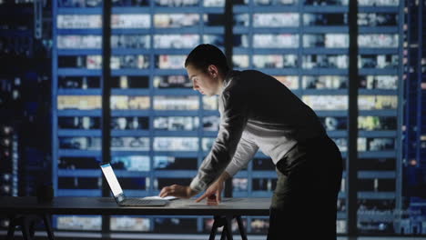 confident manager working late night in office. man standing in office lean over desk working on laptop. architects working on construction project