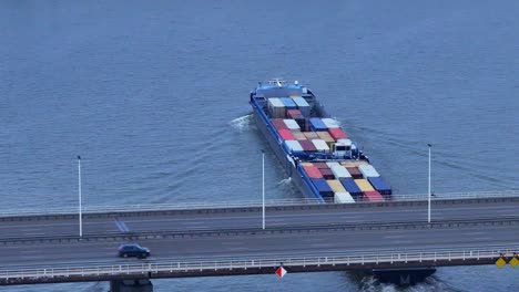 aerial view of olesia cargo container ship sailing underneath moerdijk bridge with traffic driving across