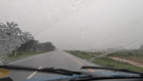 window wipers activated during a heavy storm of rain while driving on a country road in thailand