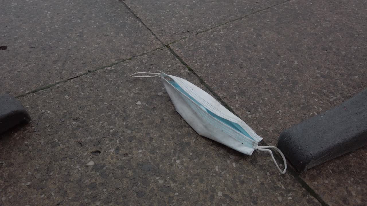 분리 장벽 사이의 도시 거리에 사용된 코로나 바이러스 얼굴 마스크 폐기물 폐기