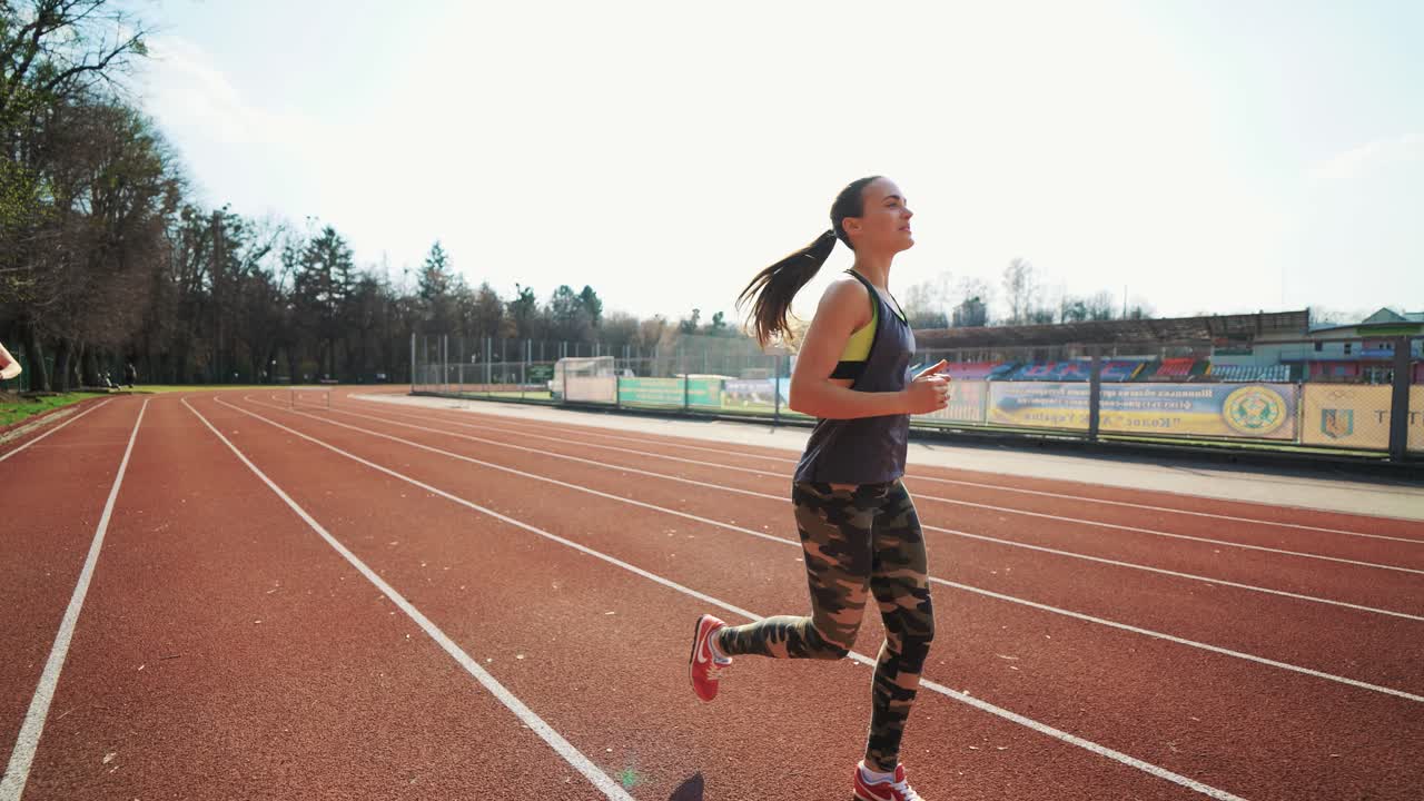 Young athletic woman running on stadium track. Beautiful body. Healthy fitness lifestyle