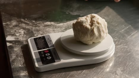 cook puts dough portion on kitchen food scales