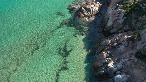 Luftaufnahme-Von-Kristallklarem-Türkisfarbenem-Wasser-Und-Felsigen-Klippen-In-Südsardinien,-Italien