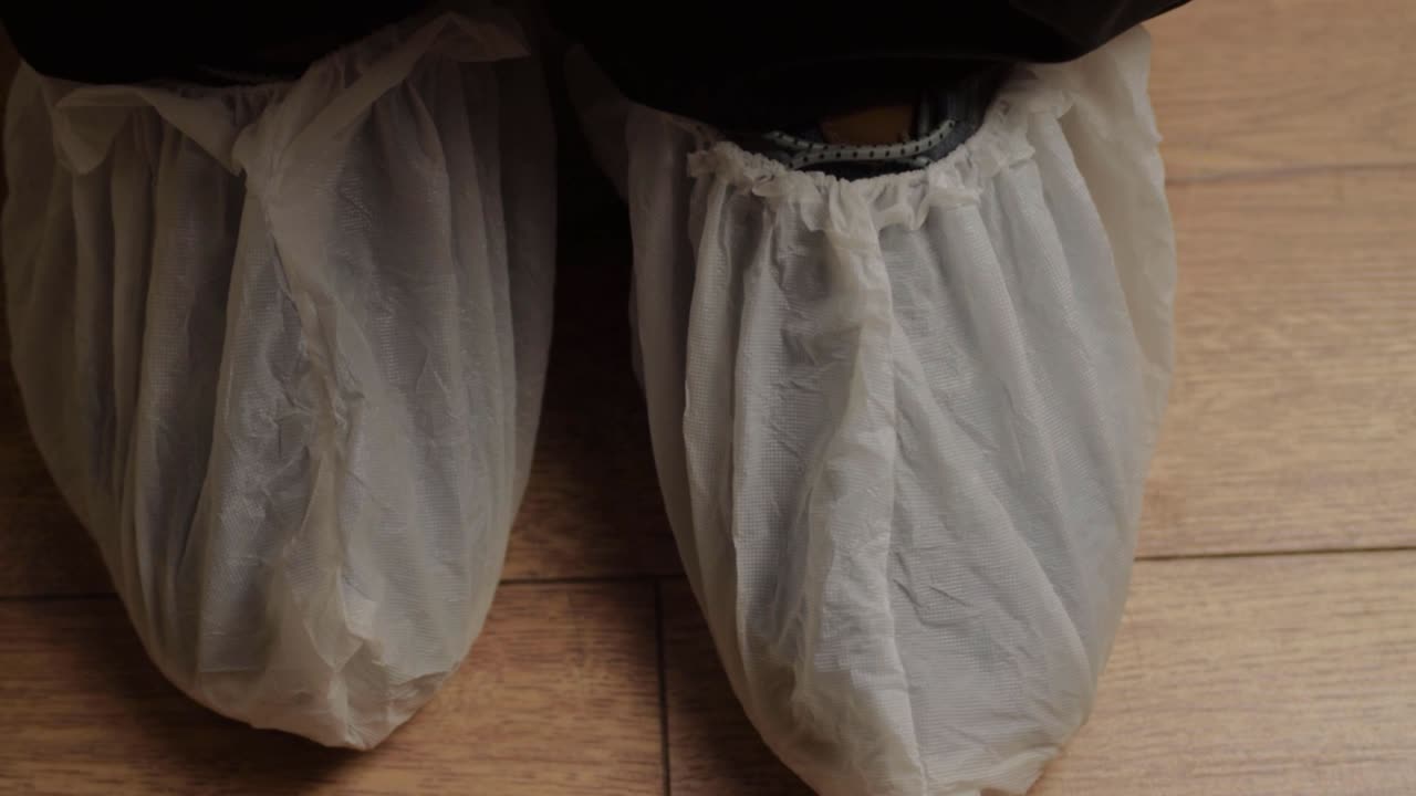 Pair of feet wearing disposable shoe protectors