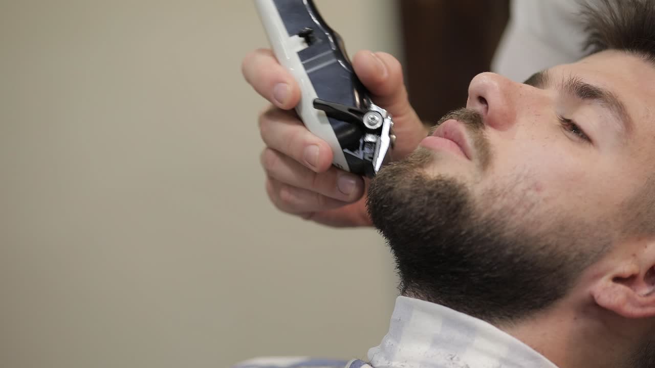 Kunde med sort skæg under skægbarbering i barbersalon. Velplejet, maskulin.
