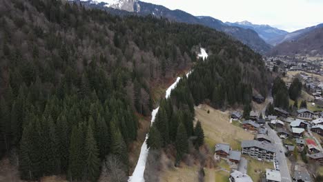 Einzelner-Weißer-Schneestreifen-Mit-Ein-Paar-Skifahrern-Darauf,-Zwischen-Den-Wäldern-In-Einem-Französischen-Skigebiet