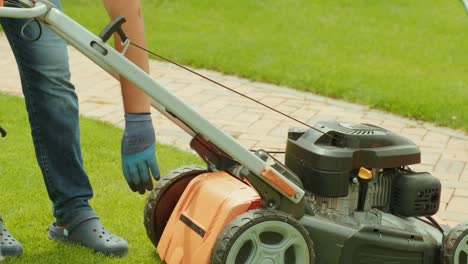 the man starts a self-propelled gasoline lawn mower and cuts high grass using a collection bag.