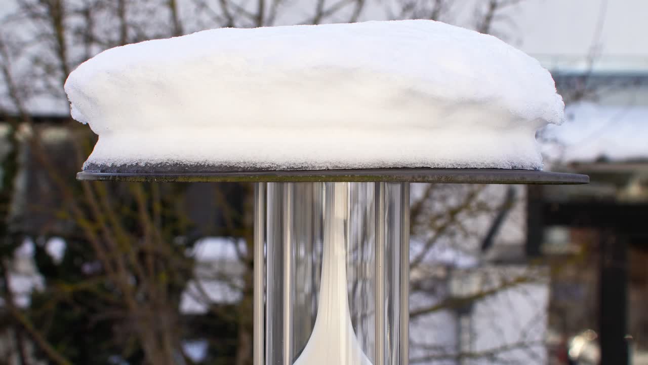 Reversed motion clip of melting snow on a lantern and waterdrops are "falling" up