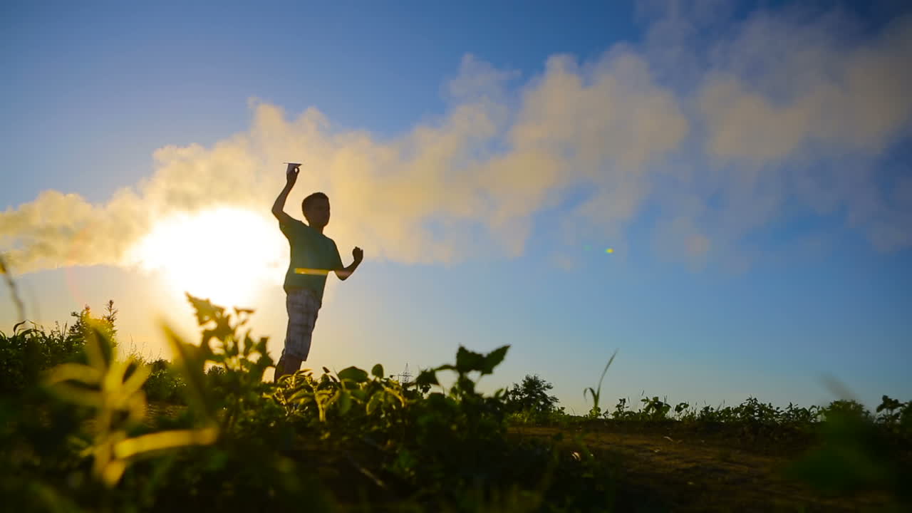 Paper Plane In Children Hand. Adorable little boy holding a paper plane near factory