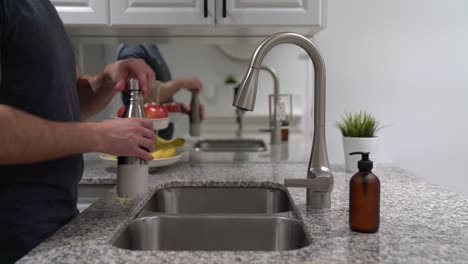 agua potable limpia y fresca del grifo de la cocina que se vierte en una botella de agua de acero inoxidable reutilizable