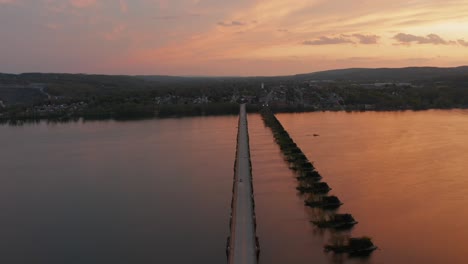 Antena-De-Un-Puente-Largo-Y-Recto-Sobre-Un-Río-Ancho-Durante-El-Amanecer-Y-El-Atardecer-Naranjas