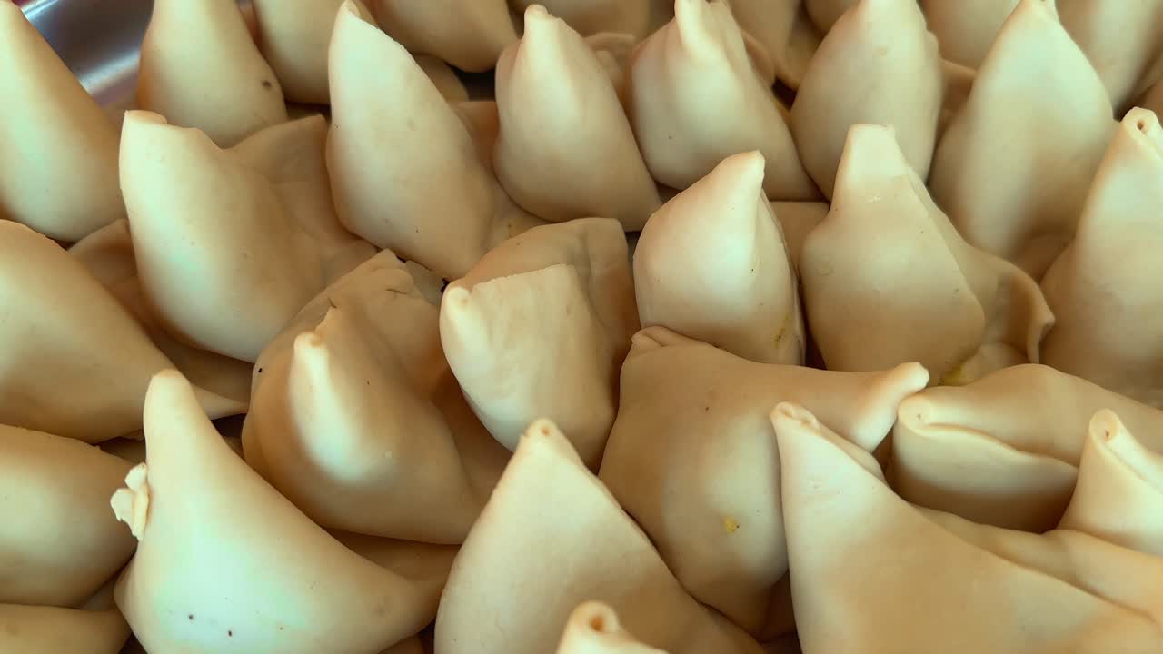 tracking shot of Uncooked raw samosa being lined up in platter for frying