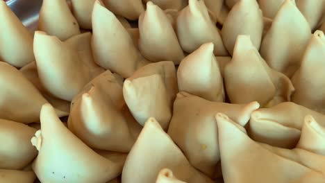 tracking shot of uncooked raw samosa being lined up in platter for frying