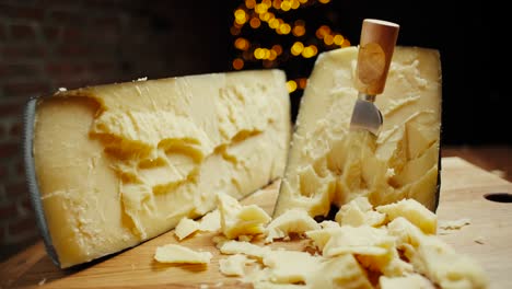 medium hard cheese head parmesan on wooden board, with cheese parmesan knifes. slide shot