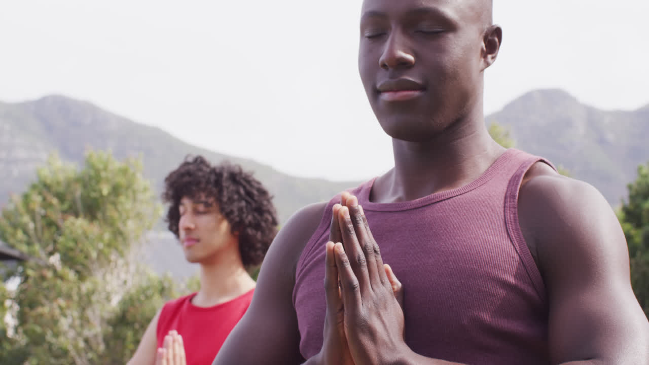Iloinen ja monimuotoinen ystäväporukka joogaamassa ja meditoimassa puutarhassa.