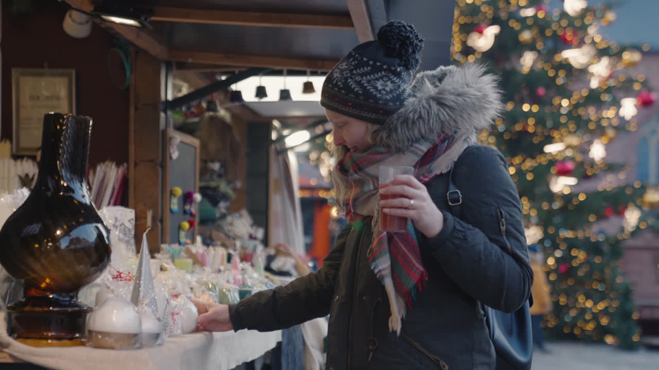 Woman visiting Christmas market in Riga, holiday spirit with festive lights and warm decorations, winter celebration holding warm cider