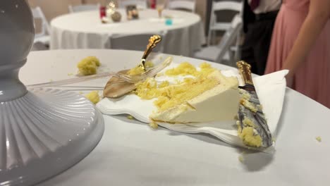 clip de torta cortada en la mesa con cuchillo y tenedor en la servilleta con el novio y las damas de honor invitados en el fondo