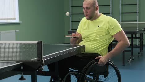 a man in a wheelchair plays ping pong. people with disabilities play table tennis. rehabilitation of the disabled. sport.