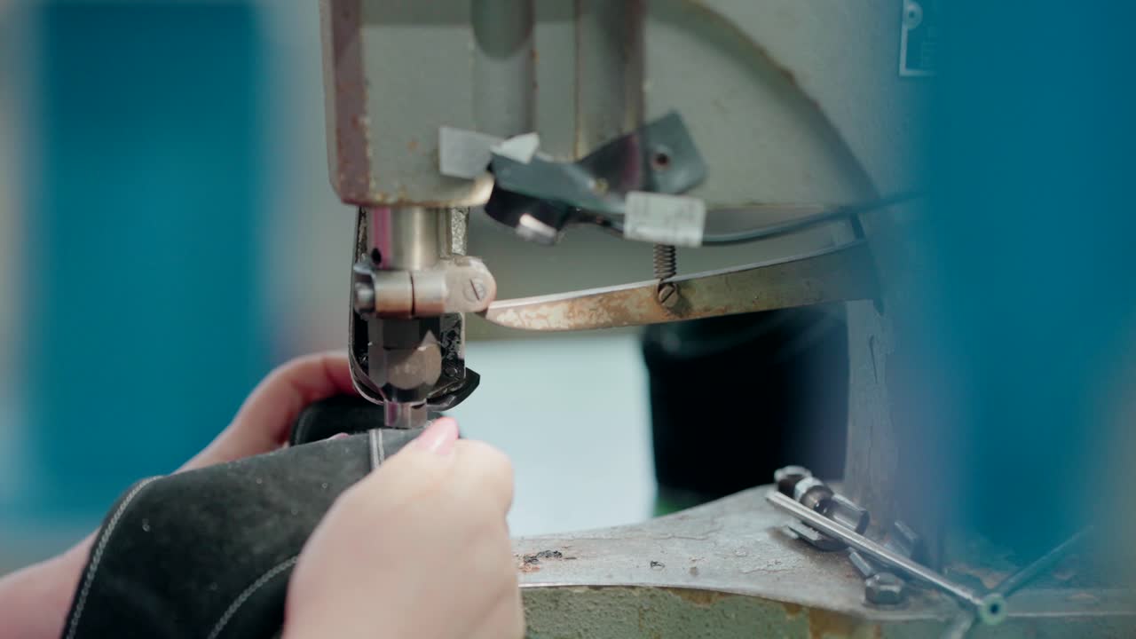 Worker punching holes for laces in a shoe during production in a factory