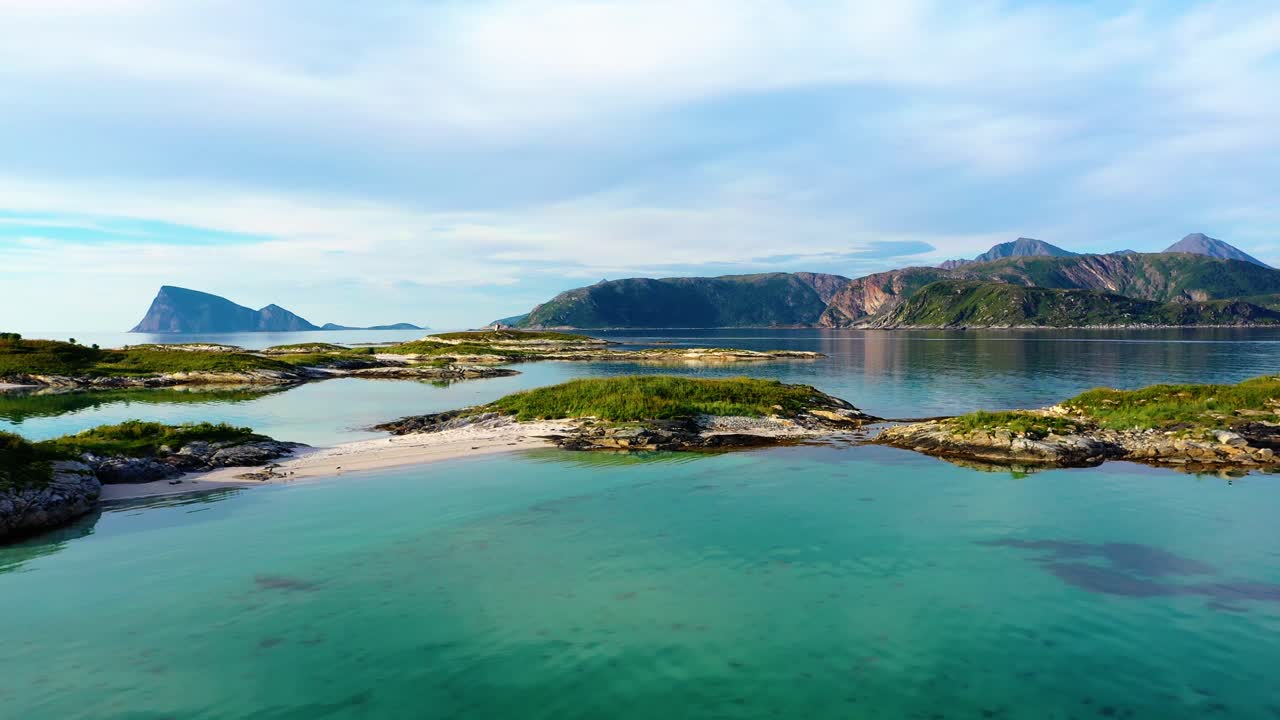 Aerial low, drone shot over small islands, white beaches and tranquil, turquoise sea, at the Arctic ocean, sunny, summer day, in Sommaroy, Norway